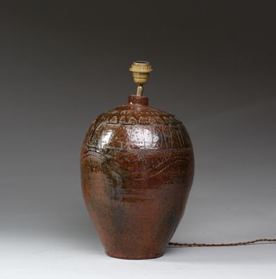 un grand vase marron surmonté d'une lampe