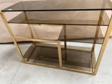 une table basse en verre et en laiton avec une étagère en verre
