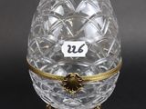 an egg shaped glass box with gold trimming and a label on it