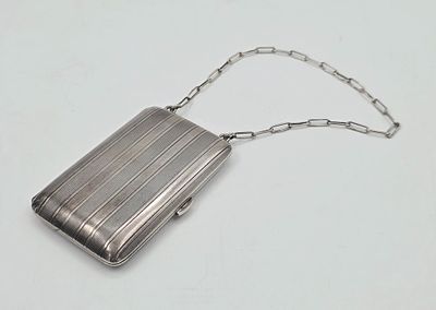 a silver purse with a chain around it on a white surface