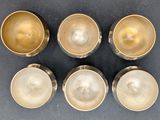 four silver bowls and a silver cup on a table