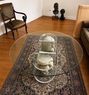 un salon avec un tapis et une table en verre sur laquelle sont posés des crânes
