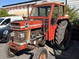 a red tractor parked in a parking lot next to a building