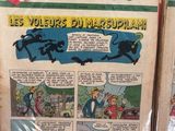 Deux bandes dessinées sont exposées sur un support rouge