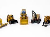 de nombreux engins de chantier miniatures posés sur une surface blanche