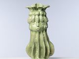 un vase vert orné d'un visage, posé sur une table