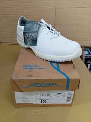 des chaussures blanches pour homme posées sur une boîte, sur une table, devant un carton