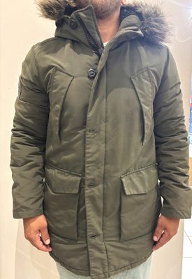 a man wearing a green parka with a fur hood