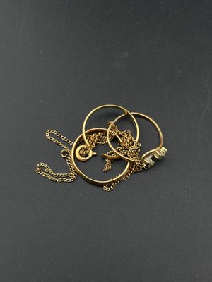 a close up of a gold necklace on a black surface