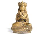 une statue en or représentant une personne assise en position du lotus