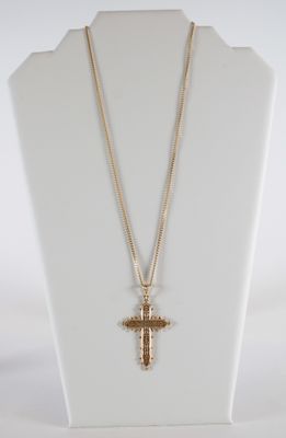 un mannequin blanc orné d'une croix et d'une chaîne en or