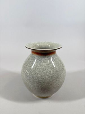 un vase gris bordé de brun, posé sur une table