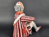 figurine of a soldier sitting on a chair with a red and white blanket