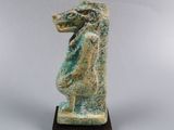 an ancient statue of a horse on a wooden base