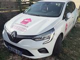 the white car is parked on the grass in front of a fence