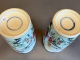 pair of blue and white vases with flowers on them sitting on a table