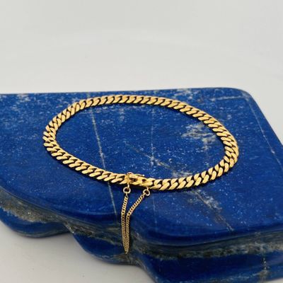 a close up of a gold chain bracelet on a blue stone