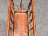 an old wooden rocking chair with a wooden seat and spindles