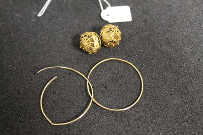 a close up of a pair of gold hoop earrings on a black surface