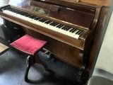 un piano dans une pièce, avec un tabouret rouge