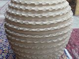 a large white vase sitting on a rug on the floor