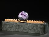 sculpture représentant une boule de marbre posée sur un bloc de pierre, sur fond noir