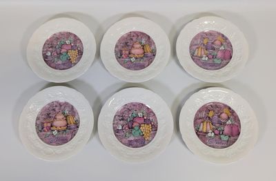 six assiettes blanches ornées de motifs violets, posées sur une surface blanche