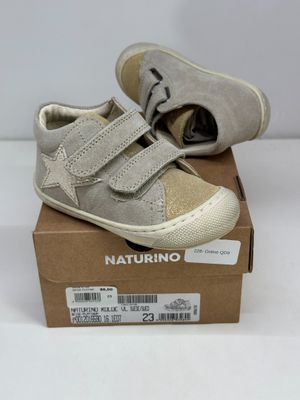 des chaussures de petit garçon dans une boîte posée sur une surface blanche