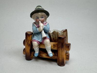 une petite figurine représentant un garçon assis sur un banc
