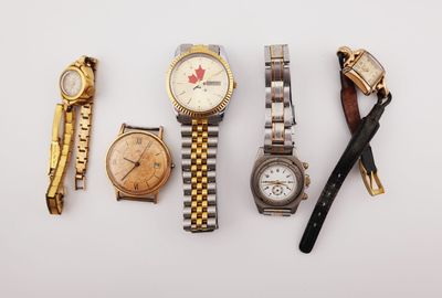 plusieurs montres différentes et un stylo posés sur une surface blanche