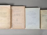 Quatre livres sont alignés sur une table devant un fond gris.