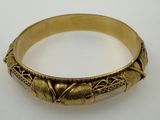 a close up of a gold bracelet on a white surface