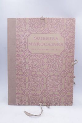 an old book with a pink cover sitting on top of a white table