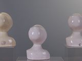 three white sculptures that are on display in a glass case
