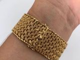 a woman ' s hand holding a gold bracelet on a white plate