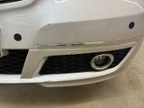 the front bumper of a white car with a number plate on it