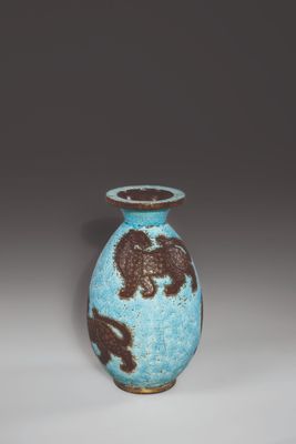 un vase bleu orné de motifs marron sur fond blanc