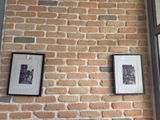 deux photos encadrées accrochées à un mur de briques près d'une fenêtre