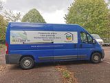 a blue van parked in a parking lot with trees in the background