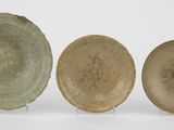 trois assiettes vertes et marron posées sur une surface blanche