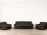 trois canapés en cuir noir et deux fauteuils dans une pièce