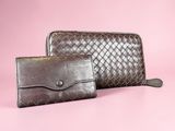 a pair of brown leather wallets on a pink background