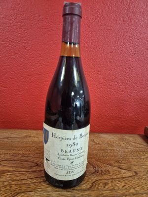 une bouteille de vin posée sur une table en bois, près d'un mur rouge