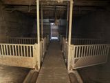 a long wooden walkway leading to two stalls in a barn