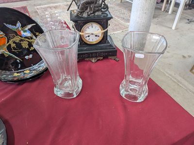 three glass vases sitting on a table with a clock in the background
