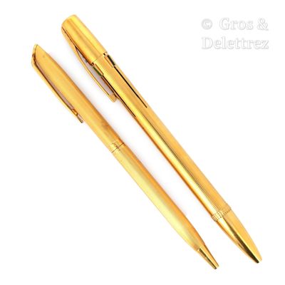 deux stylos dorés posés l'un à côté de l'autre sur une surface blanche