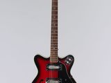 an electric guitar hanging from a string on a white wall