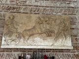 a stone relief of a man riding a horse and a woman on a carriage