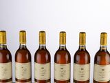 six bottles of wine are lined up in a row on a table