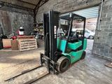 un chariot élévateur dans un entrepôt, avec des palettes au premier plan